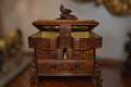 19th-century Black Forest carved walnut jewelry casket open with double doors, all-over floral carved panels, carved bird finial on lid, gold satin interior, lower storage drawer, and bracket feet