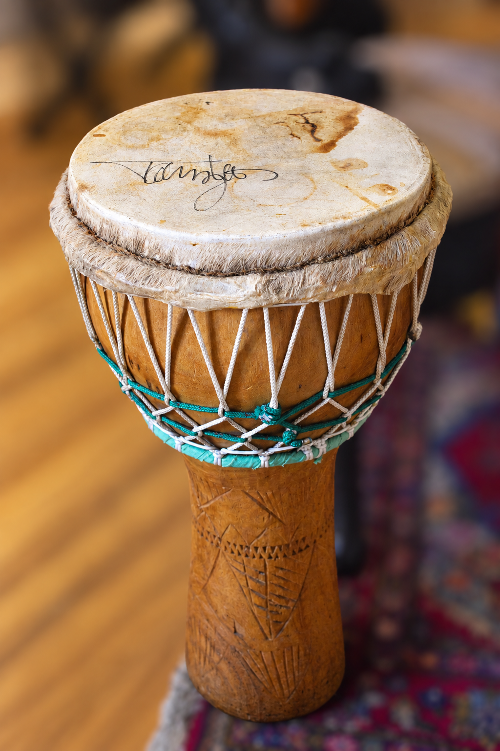 Goblet-shaped wooden hand drum with rope-laced sides, carved details, and a signature attributed to Tommy Lee on the marked drumhead