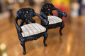 Pair of 19th-century Chinese Qing Dynasty throne chairs with dark carved frames, curved arms, and light patterned seat cushions