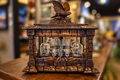 Carved oak Black Forest tantalus with a bird finial and displayed glass decanters and tumblers