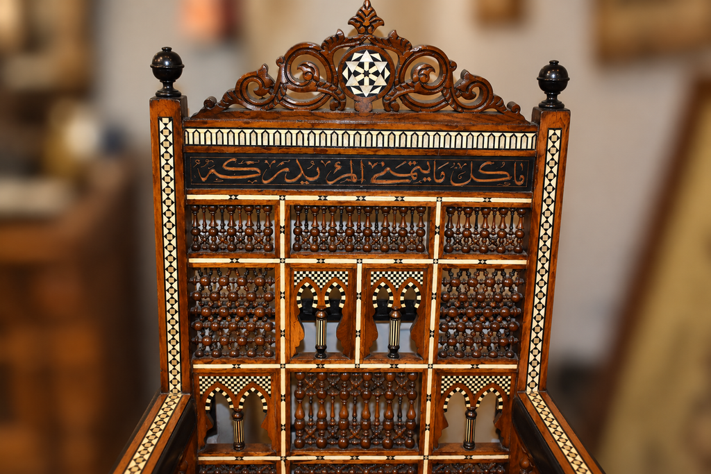 Close-up of the Middle Eastern armchair’s carved back, showing geometric mother-of-pearl inlay, turned wood details, and decorative script