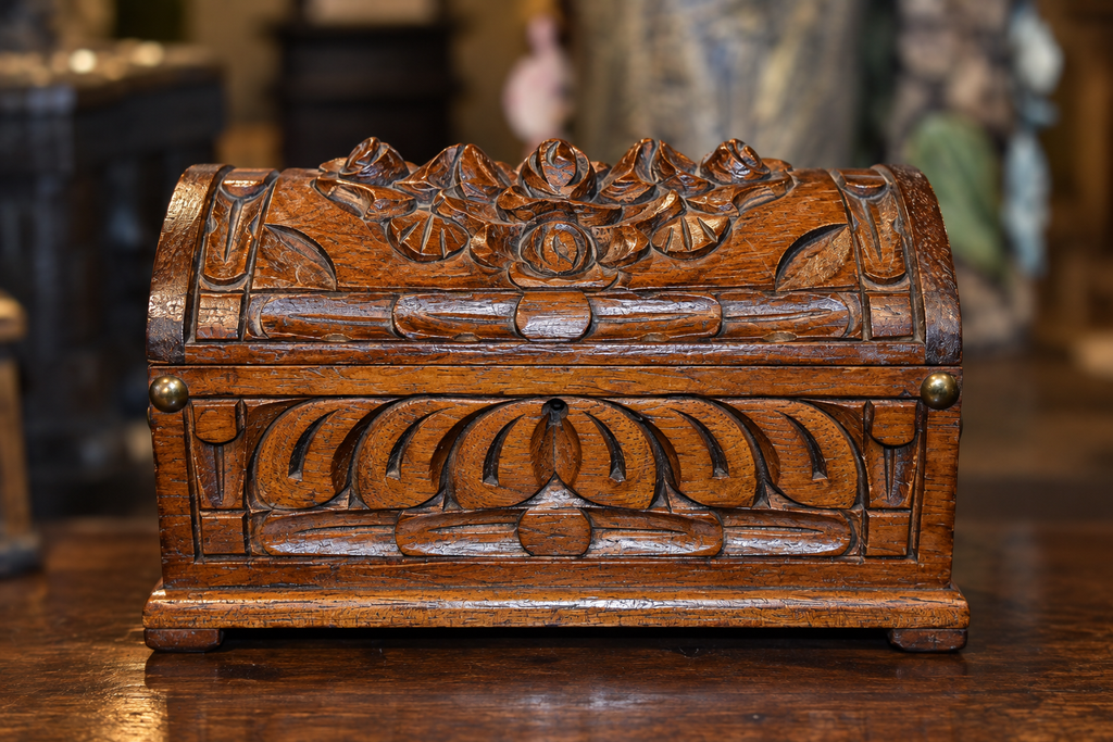 Front view of a hand-carved oak jewelry box with a domed lid, raised floral and scrolling foliage motifs, and decorative carved borders.