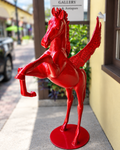 A red winged horse sculpture standing on a round base.